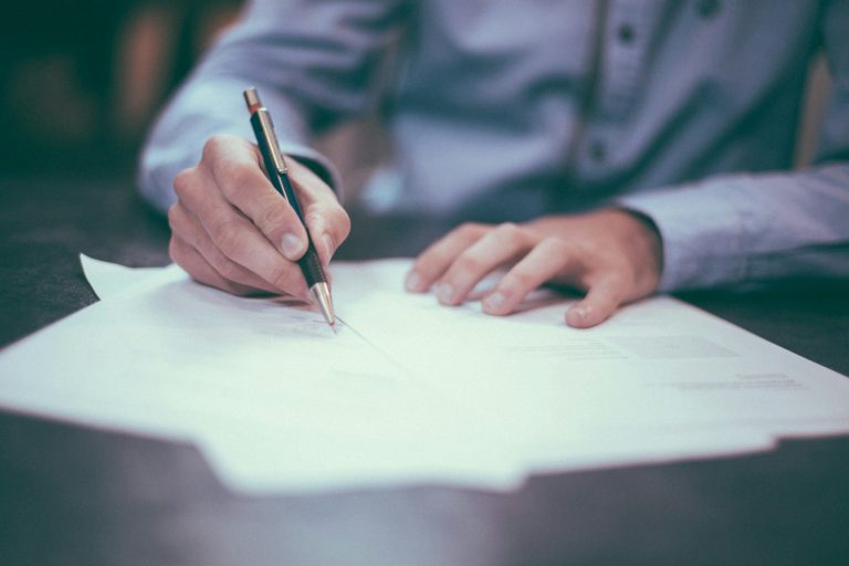 Firma de Acuerdo Mano escribiendo en una hoja de papel con un bolígrafo.